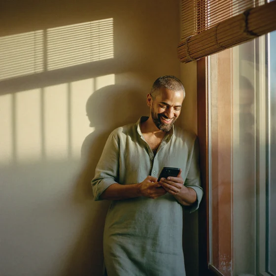 A consultant smiling at his phone after a client payment notification