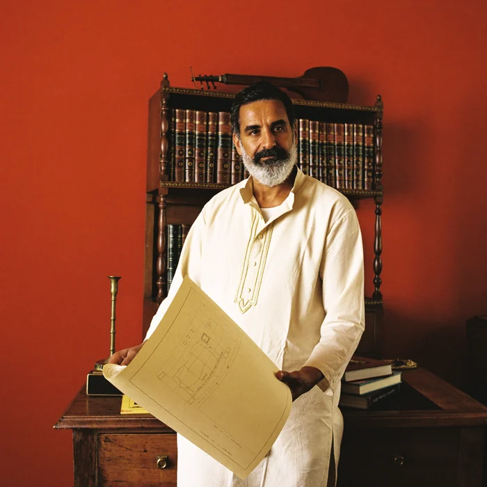 A Vastu consultant in a heritage-styled study, holding a floor plan
